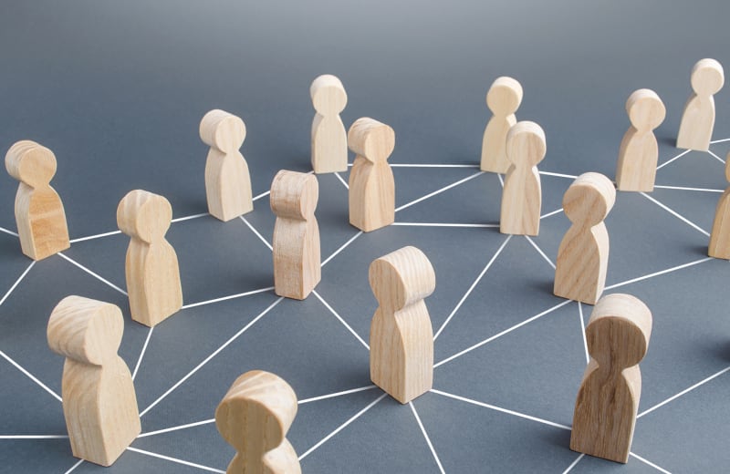 社会的ネットワーク、チームワーク、コミュニティを象徴する木製の人形が線で繋がっている様子